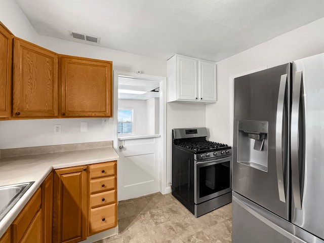 kitchen featuring light countertops, visible vents, appliances with stainless steel finishes, brown cabinetry, and a sink