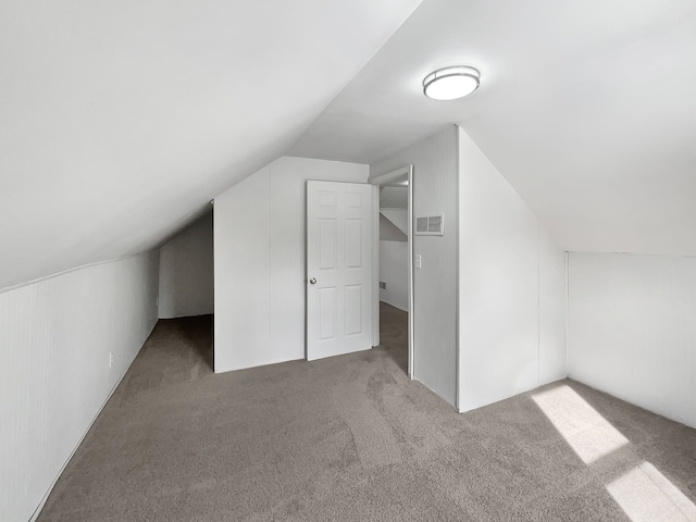 bonus room featuring lofted ceiling, visible vents, and light colored carpet