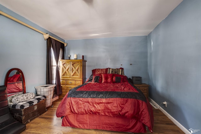 bedroom with wood finished floors, visible vents, and baseboards