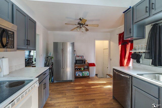 kitchen with dark wood-style flooring, stainless steel appliances, light countertops, ceiling fan, and a sink