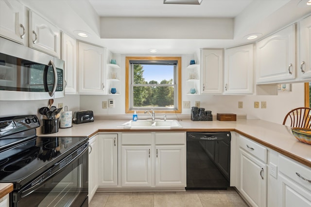 kitchen with a sink, black appliances, light countertops, and white cabinetry