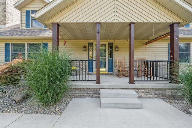 entrance to property with a porch and roof with shingles