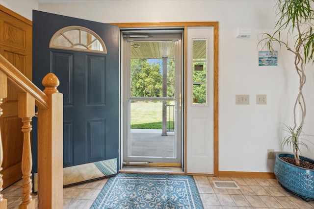 foyer with stairway, light tile patterned flooring, visible vents, and baseboards