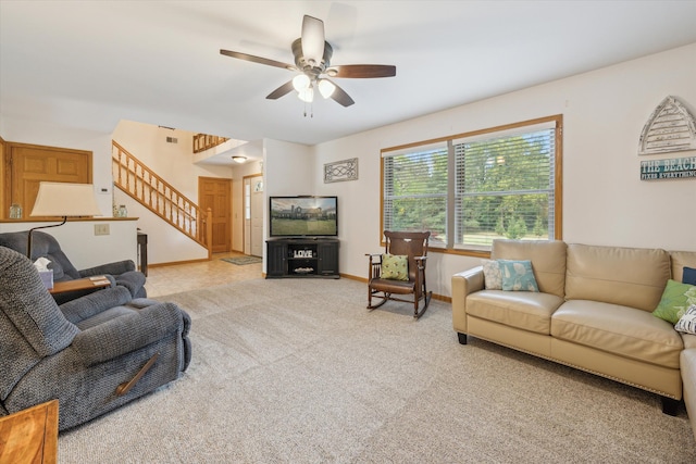 living area with light carpet, ceiling fan, stairs, and baseboards