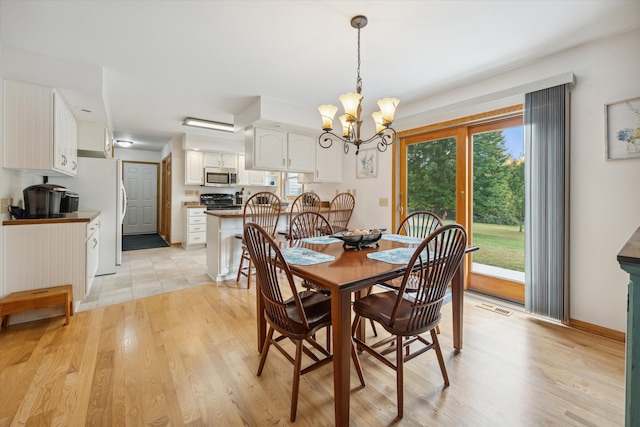 dining area featuring a chandelier, light wood-type flooring, visible vents, and baseboards