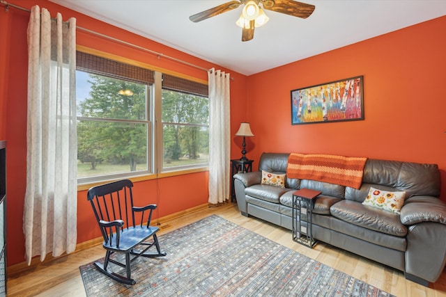 living area featuring wood finished floors, a ceiling fan, and baseboards