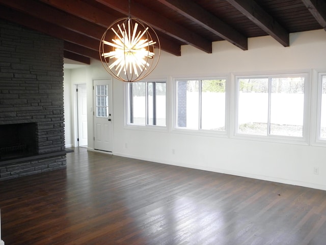 unfurnished living room with beam ceiling, an inviting chandelier, dark wood-type flooring, a stone fireplace, and baseboards