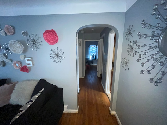 corridor with baseboards, arched walkways, and dark wood-type flooring