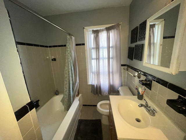 full bathroom with toilet, shower / tub combo, vanity, tile walls, and wainscoting