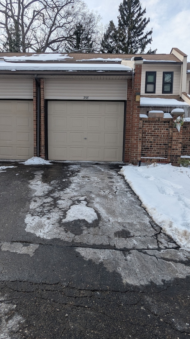 snow covered garage featuring driveway