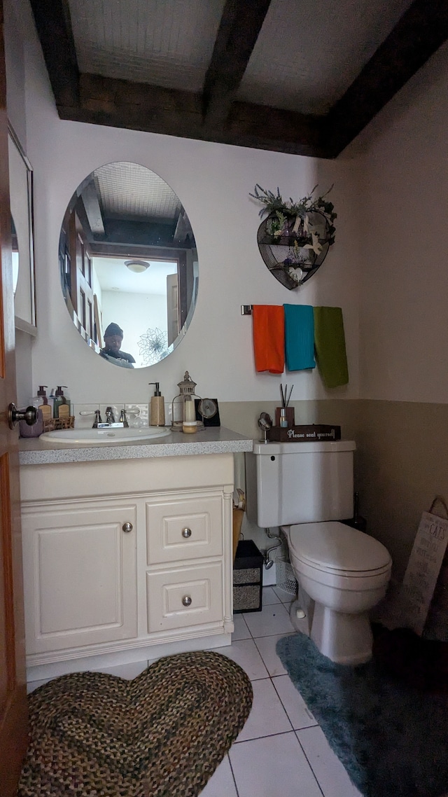 bathroom featuring beam ceiling, tile patterned flooring, toilet, and vanity