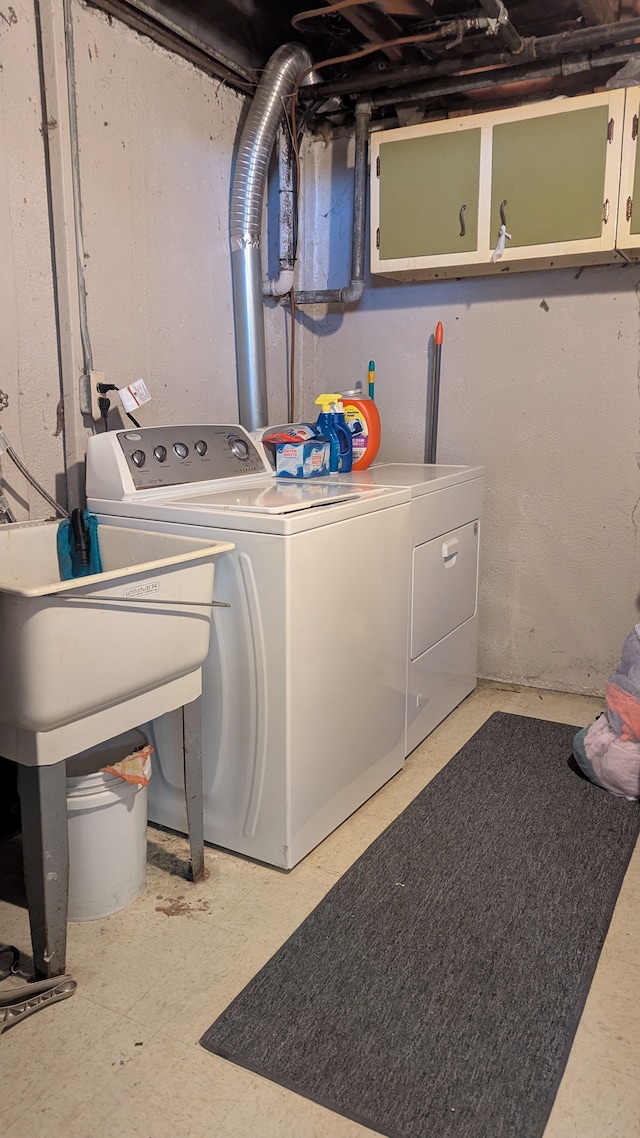 clothes washing area with washer and dryer and cabinet space