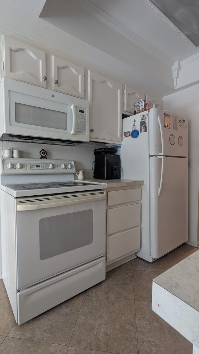 kitchen featuring light tile patterned floors, white appliances, crown molding, and light countertops