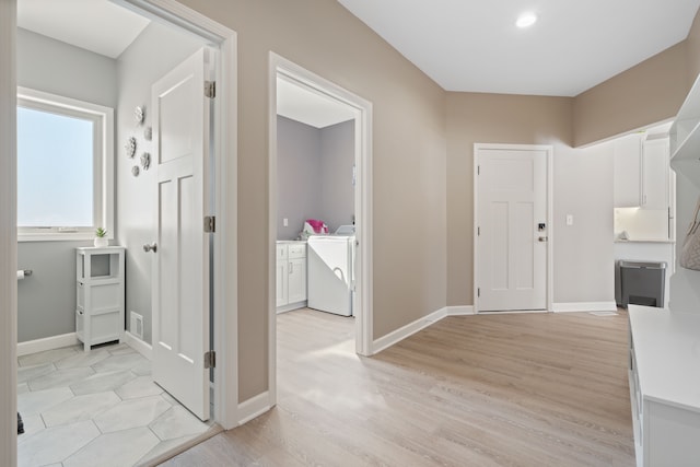 hallway featuring washer and dryer, visible vents, baseboards, and light wood-style flooring