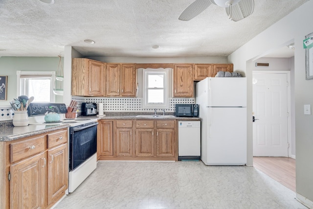 kitchen featuring white appliances, plenty of natural light, a sink, and tasteful backsplash