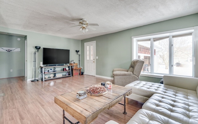 living area featuring ceiling fan, a textured ceiling, baseboards, and wood finished floors