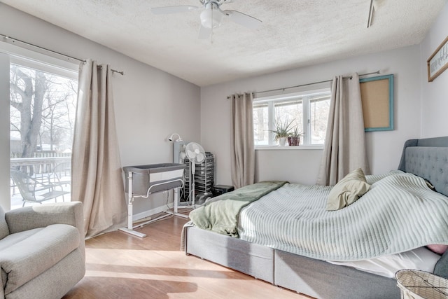 bedroom with a textured ceiling, ceiling fan, and light wood-style floors