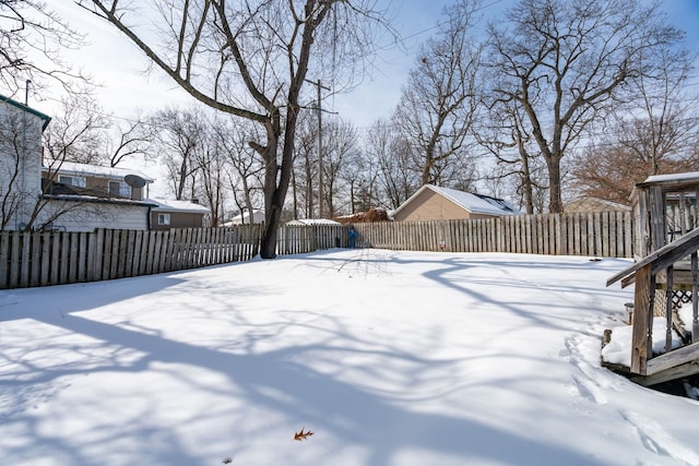 snowy yard with a fenced backyard