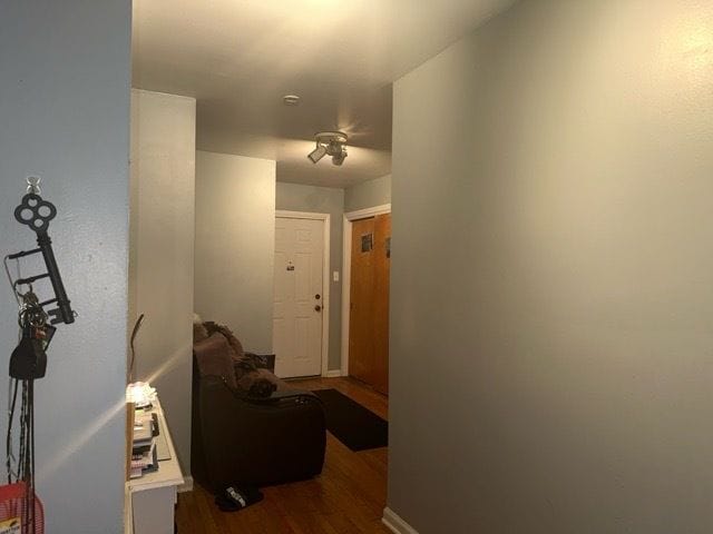 corridor featuring dark wood-style floors and baseboards