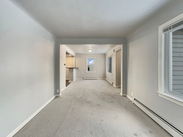 interior space featuring a baseboard heating unit, a baseboard radiator, light carpet, and baseboards