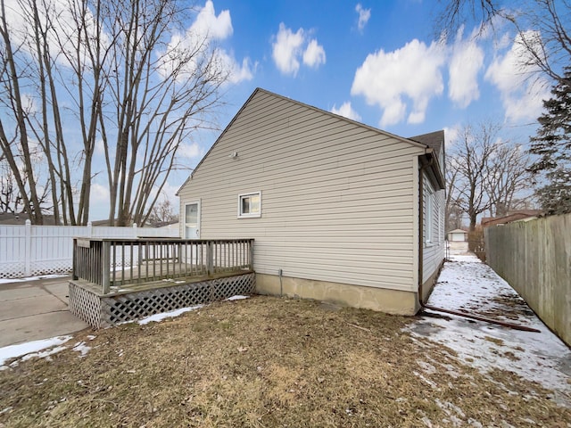 view of snow covered exterior featuring a fenced backyard and a wooden deck