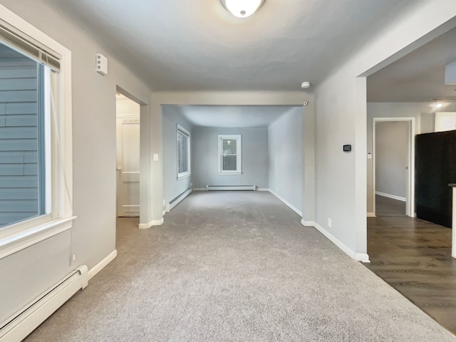 carpeted spare room featuring a baseboard radiator and baseboards