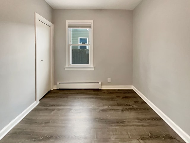 unfurnished bedroom with dark wood-style floors, a baseboard radiator, and baseboards