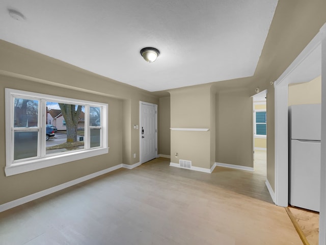 empty room with visible vents, a water view, light wood-style flooring, and baseboards