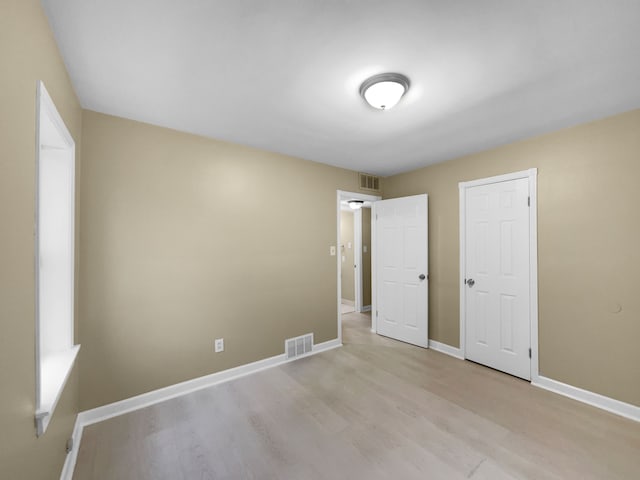 unfurnished bedroom with light wood finished floors, visible vents, and baseboards