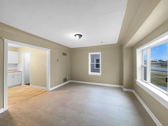 unfurnished room with baseboards, visible vents, and light wood-style flooring