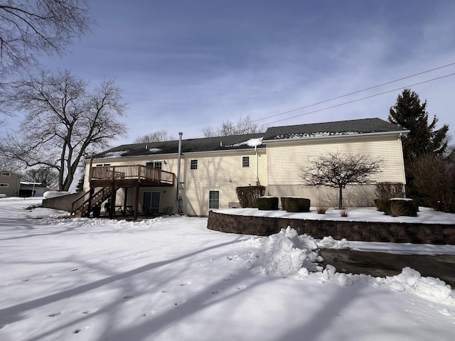 snow covered back of property featuring a deck and stairway