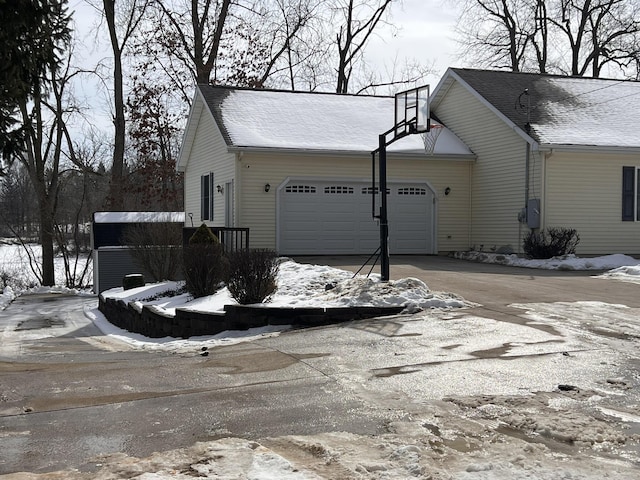 view of snowy exterior with driveway and an attached garage