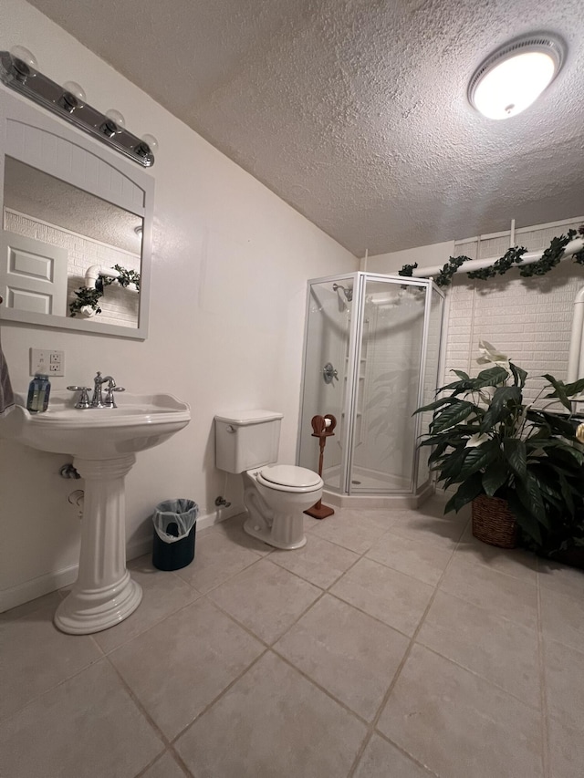 full bath with toilet, a shower stall, a textured ceiling, tile patterned flooring, and baseboards