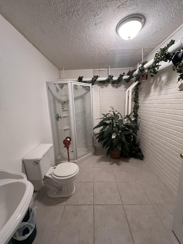 full bath with a stall shower, toilet, tile patterned floors, a textured ceiling, and a sink