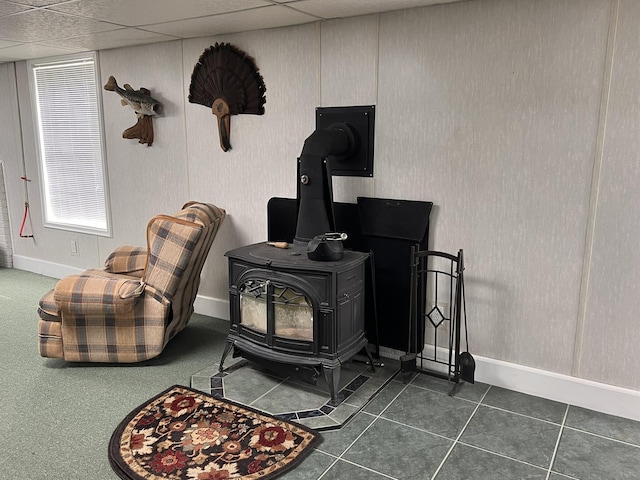 room details featuring a paneled ceiling, a wood stove, and baseboards