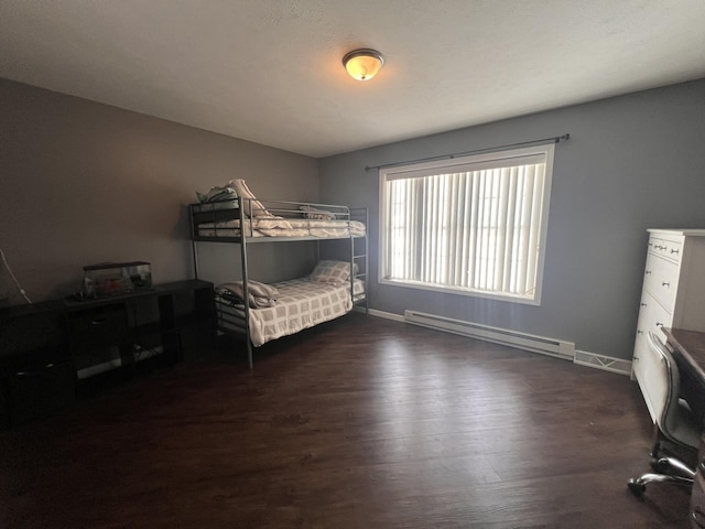 bedroom featuring dark wood-style floors, baseboards, and a baseboard heating unit