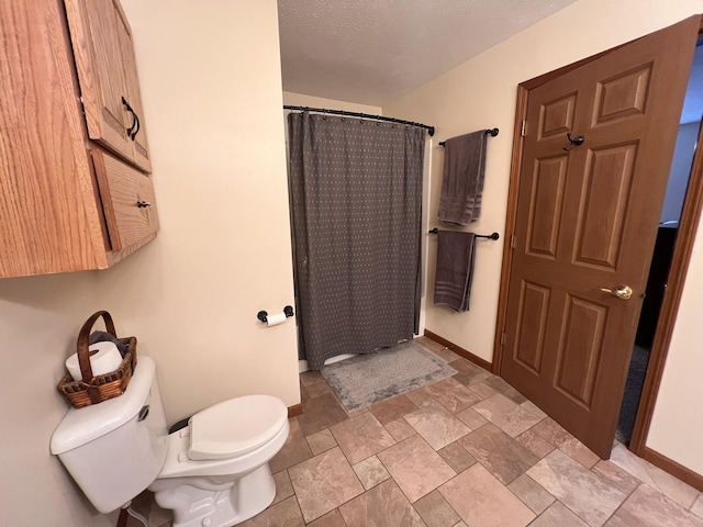 bathroom with a shower with shower curtain, baseboards, a textured ceiling, and toilet