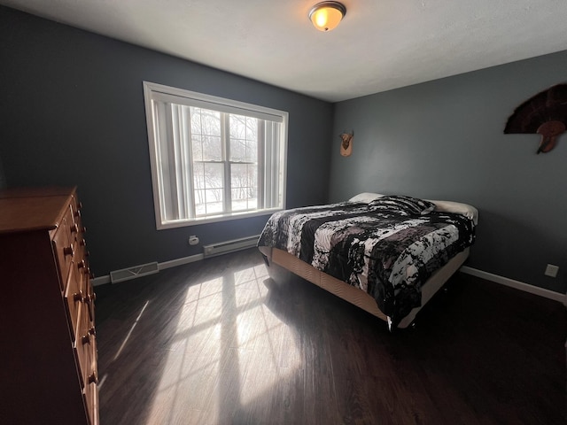 bedroom featuring baseboards, visible vents, baseboard heating, and wood finished floors