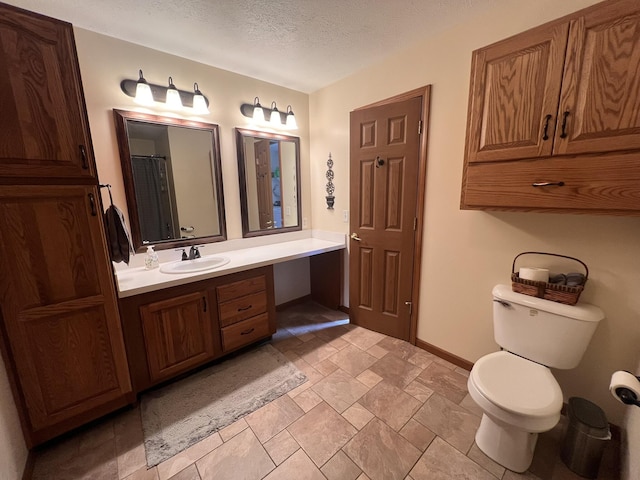 full bath with toilet, baseboards, a textured ceiling, and vanity