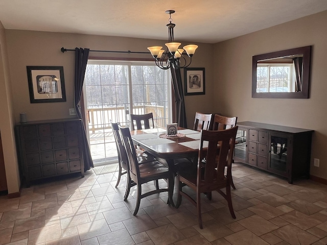 dining area featuring an inviting chandelier, stone finish flooring, and baseboards