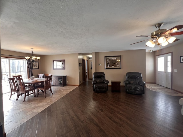 dining room with a textured ceiling, baseboards, wood finished floors, and ceiling fan with notable chandelier