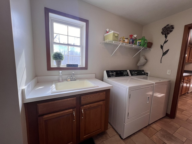 clothes washing area featuring cabinet space, a sink, and separate washer and dryer