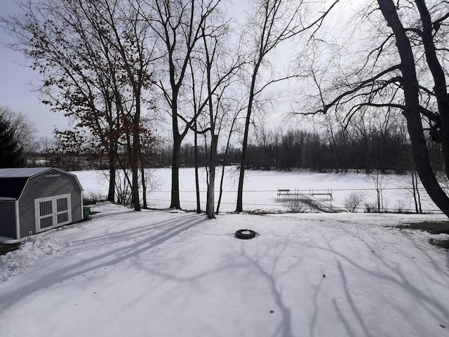 snowy yard featuring a storage unit, an outdoor structure, and fence