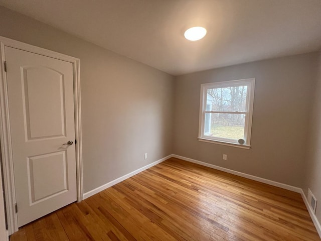 spare room with light wood-style flooring, visible vents, and baseboards