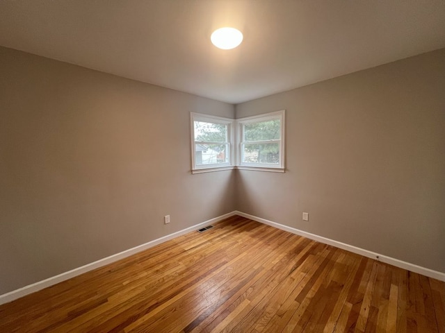 empty room featuring light wood-type flooring, visible vents, and baseboards