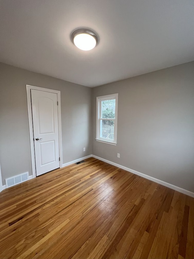 empty room featuring light wood-type flooring, visible vents, and baseboards