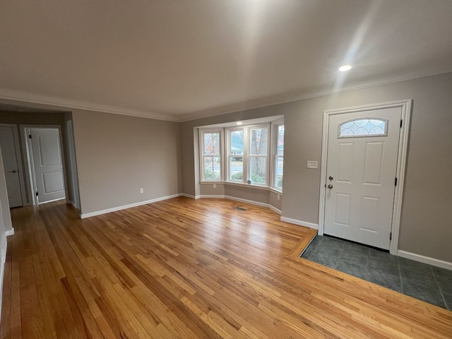 entrance foyer featuring ornamental molding, baseboards, and wood finished floors