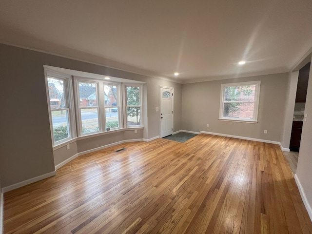 unfurnished living room with recessed lighting, visible vents, baseboards, light wood-style floors, and ornamental molding