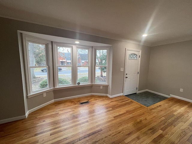 entryway with wood-type flooring, crown molding, and baseboards