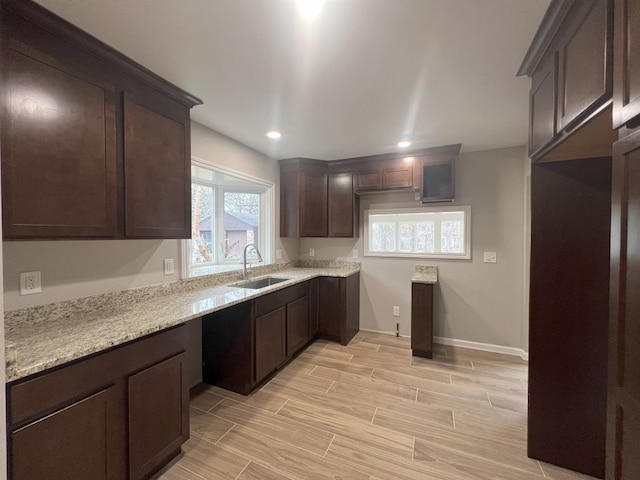 kitchen featuring dark brown cabinetry, recessed lighting, a sink, baseboards, and wood tiled floor